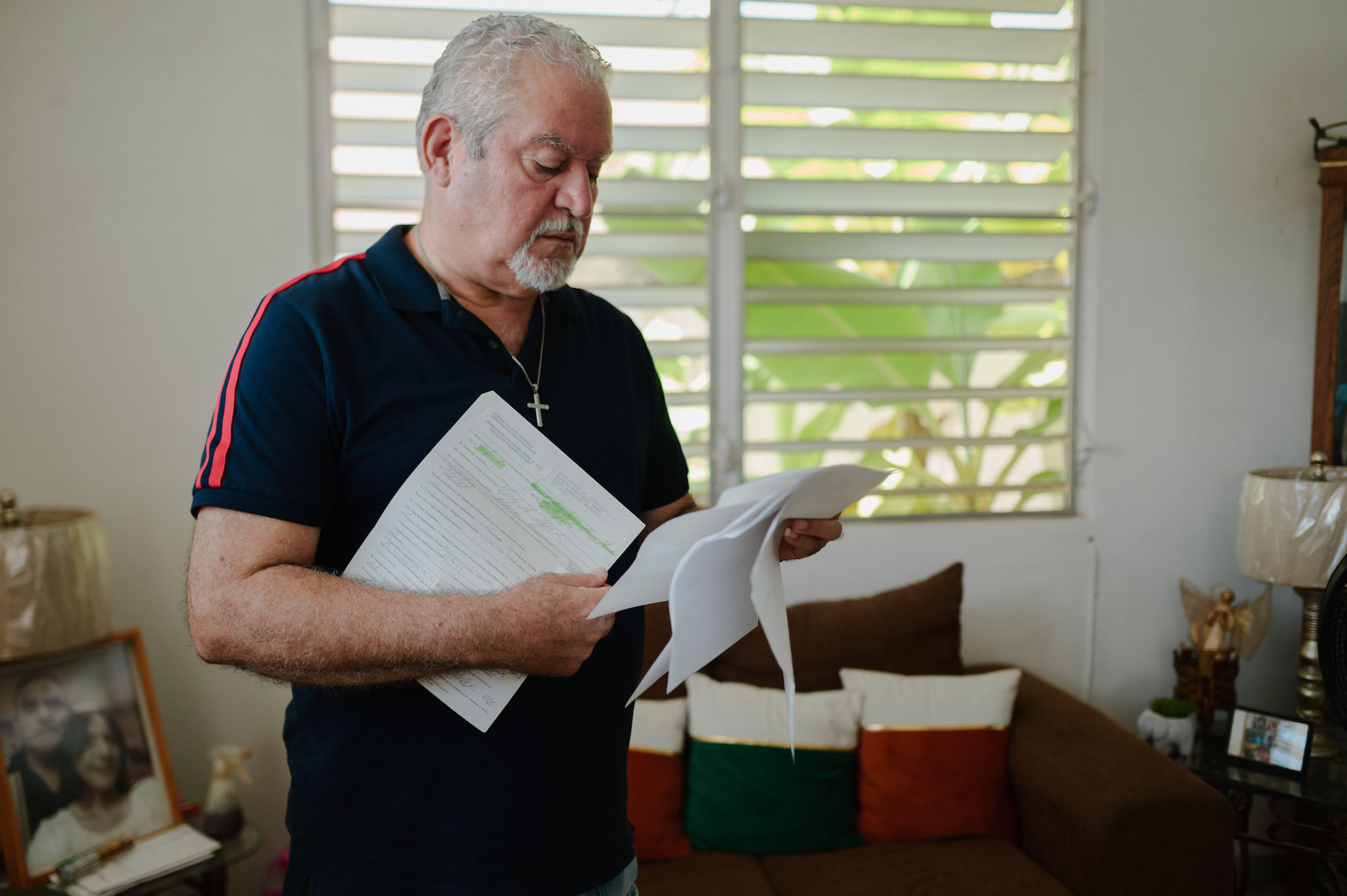 A man holds several leaves of paper, looking thoughtful