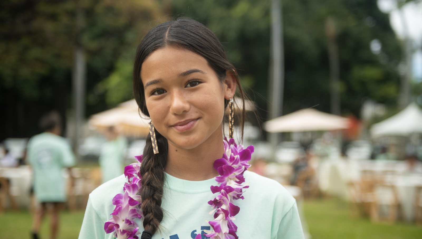 Kaliko smiles wearing a lei on a sunny day outside Iolani Palace in Honolulu.