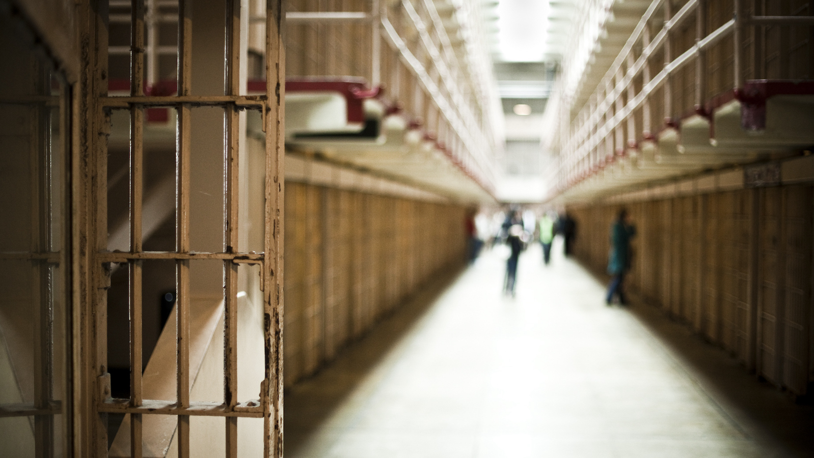 A view down a prison corridor, showing bars and cell doors.